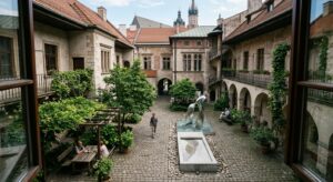 A high-angle, professional editorial photograph of a secret, quiet courtyard in Kraków, blending his